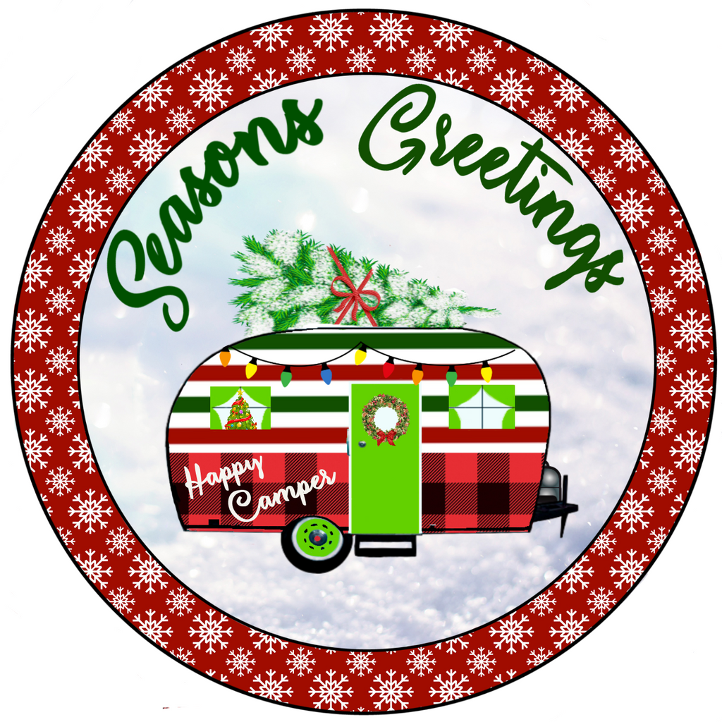 8 inch round metal wreath sign has Seasons Greetings in green with a classic camper all decked out for Christmas with buffalo plaid, red/green stripes, wreaths, lights and a tree on top set against a snowy background.