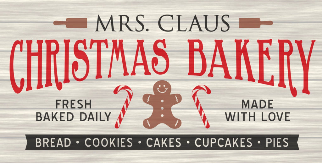 12 inch metal wreath sign printed against a faded brown shiplap design with Mrs. Claus Christmas Bakery printed with gingerbread and candy cane accents.