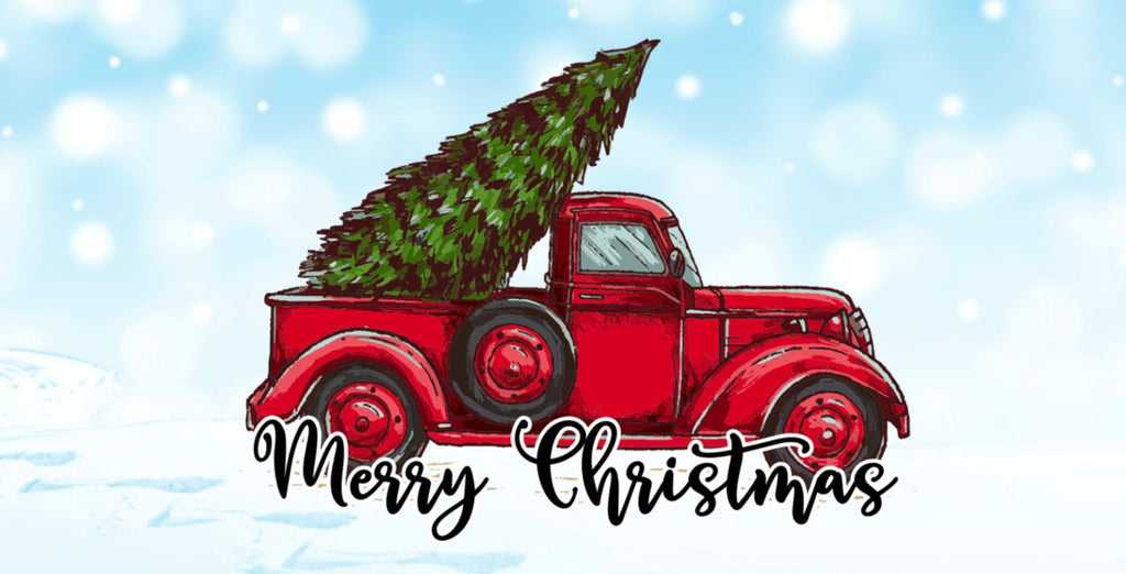 12 inch metal wreath sign with an antique red truck transporting a large pine tree with Merry Christmas written in black atop a snowy background.
