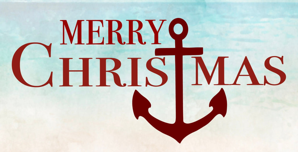 12 inch metal wreath sign with Merry Christmas printed in red and accented with a large anchor set against a faded beach background.